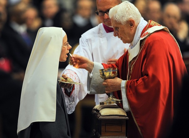 Pope Benedict XVI gives communion to a n